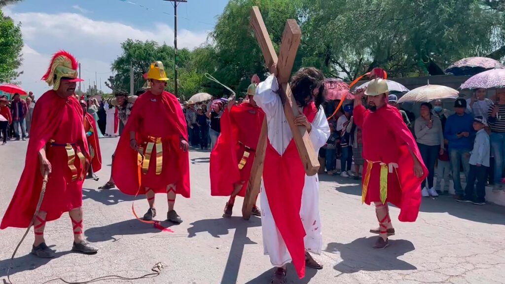 Participants in red robes act out a Semana Santa scene during a Holy Week reenactment outdoors.