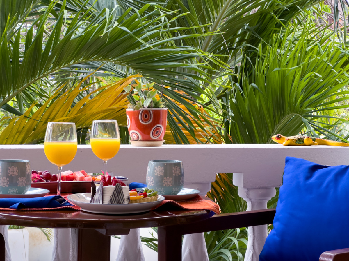 Private balcony at Apartment #6 with breakfast table and tropical palm views in Puerto Morelos