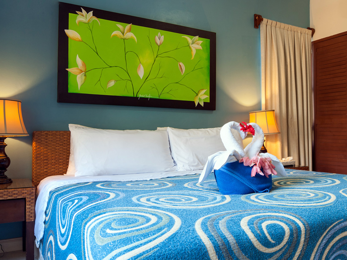 Bright bedroom at Apartment #7 at Abbey 2 with colorful bedding and decorative towel art
