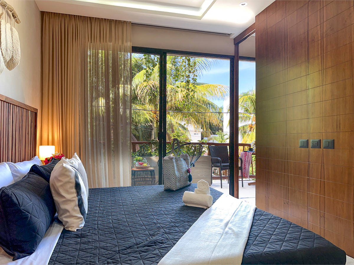 Modern bedroom at Casa Alba with wood accents and balcony view in Puerto Morelos