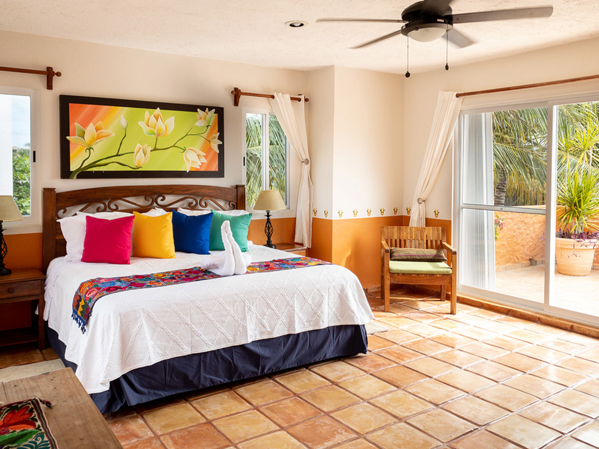 Bright bedroom at Casa Mulder with colorful accents and garden access in Puerto Morelos