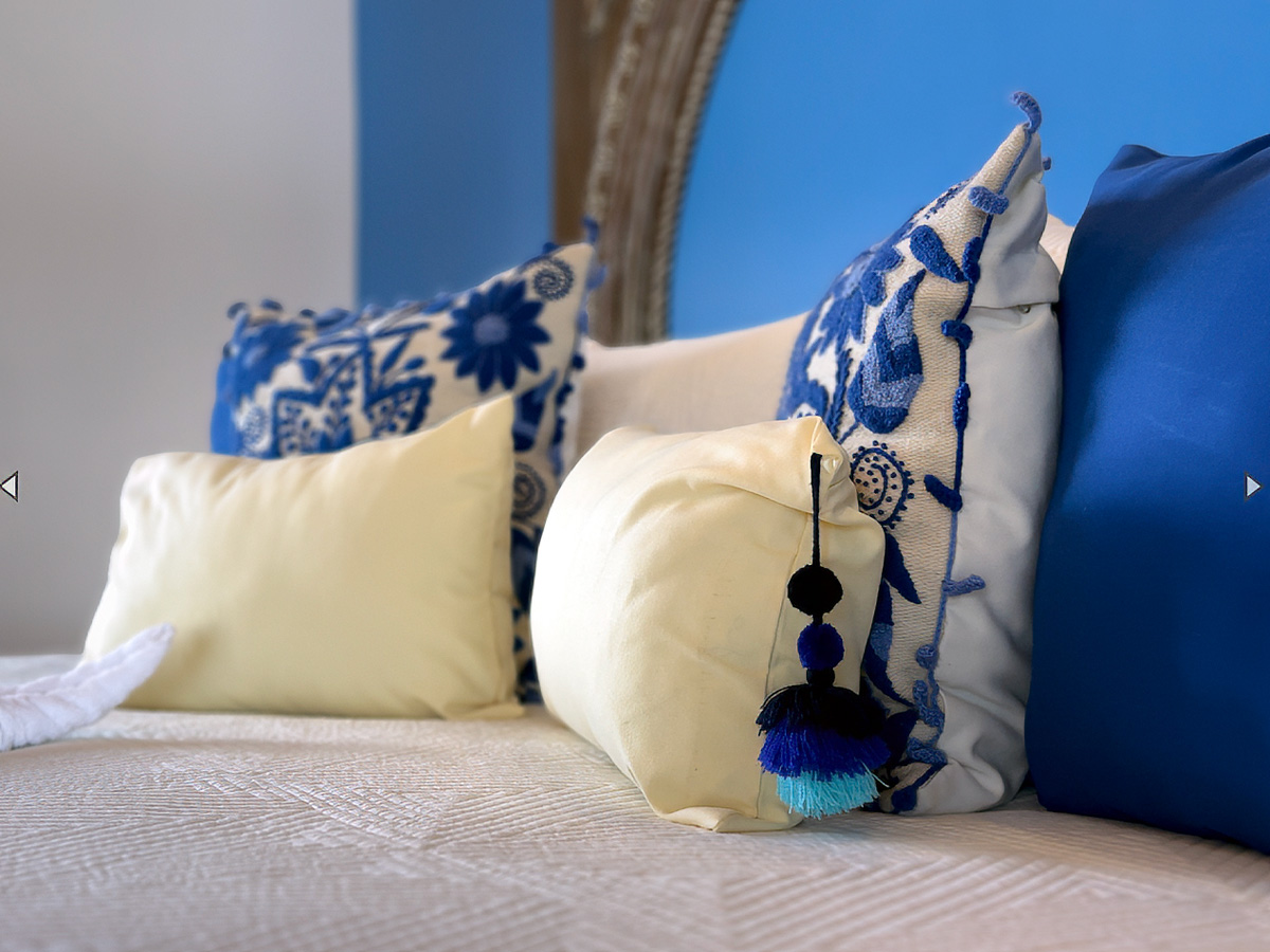 Bedroom detail at Casa Tequila with blue accents and embroidered pillows in Puerto Morelos