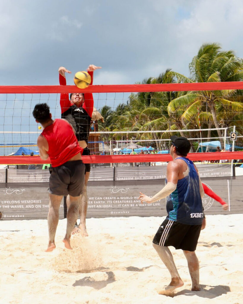 Beach volleyball player jumps to hit the ball at the Puerto Morelos festival.