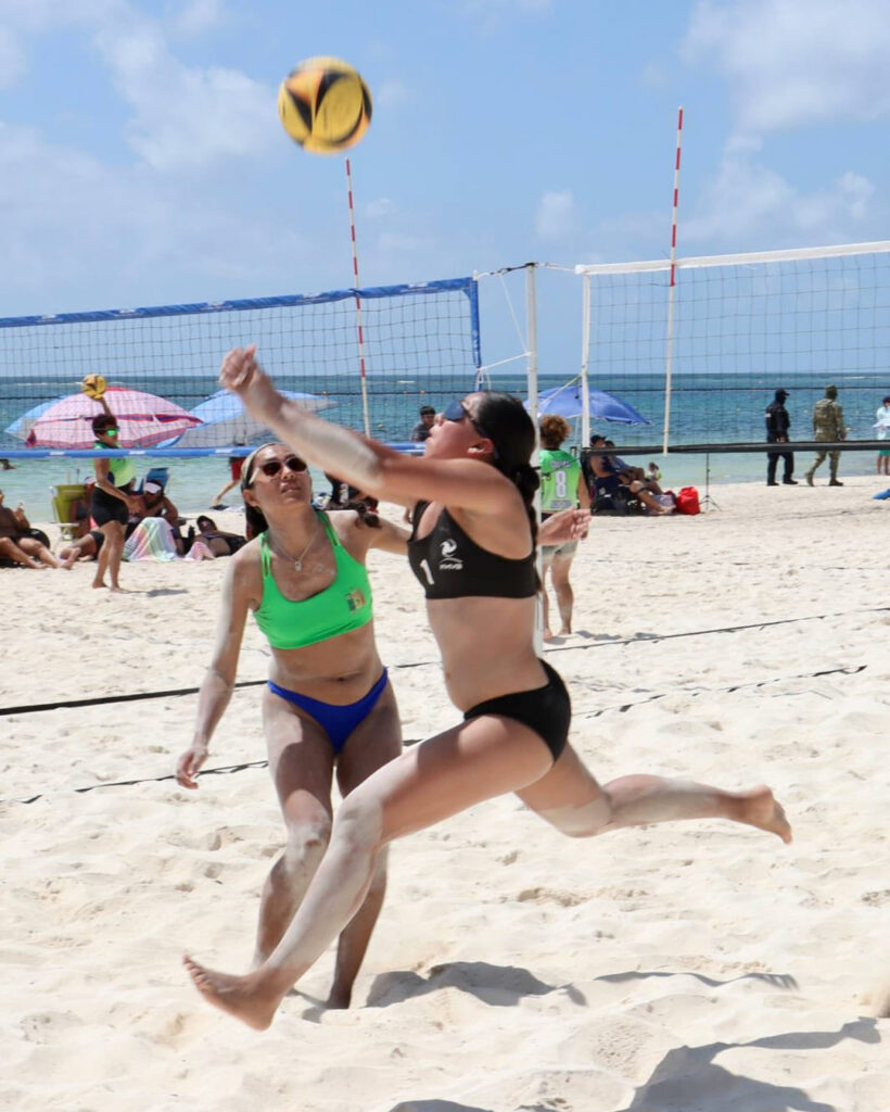 Beach volleyball player jumps to hit the ball at the Puerto Morelos festival.