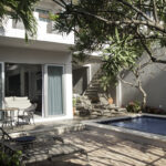 Shaded patio and pool area at Casa Agua Azul with tropical trees.