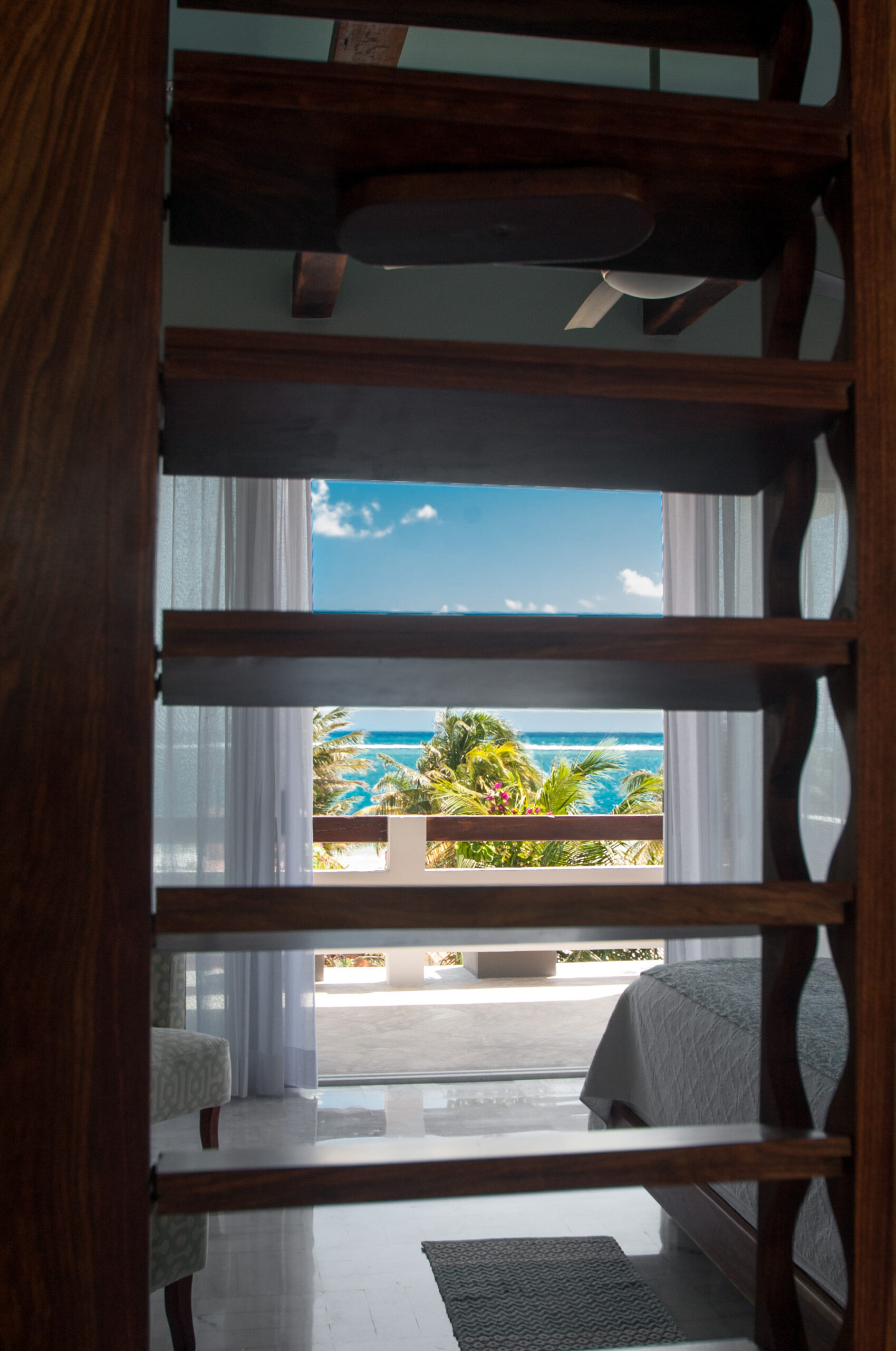 Wood staircase inside Casa Agua Azul with Caribbean views through the doorway.