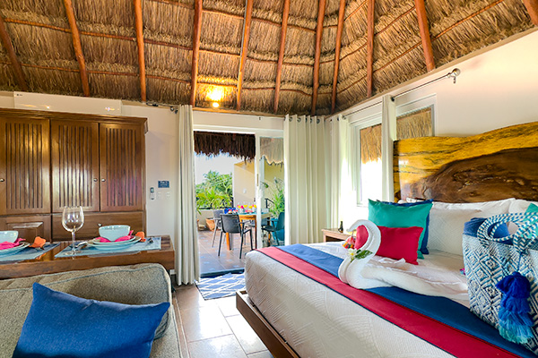 Catalina 3 studio with king bed, palapa ceiling, blue sofa, and doors to a private terrace.