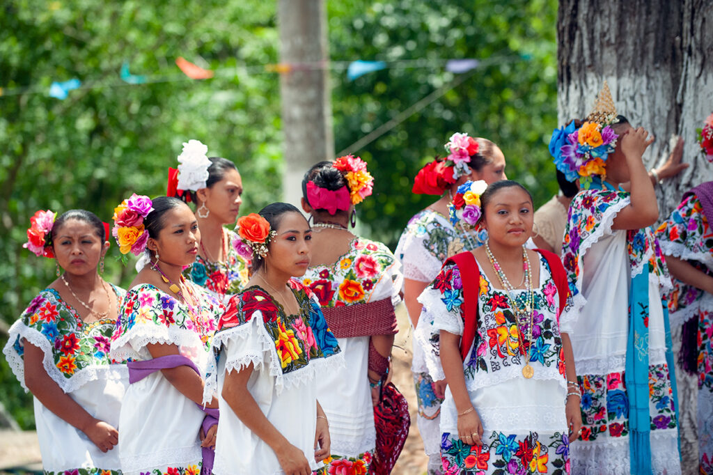 Maya women in colorful traditional dresses gather for a community celebration near Puerto Morelos.