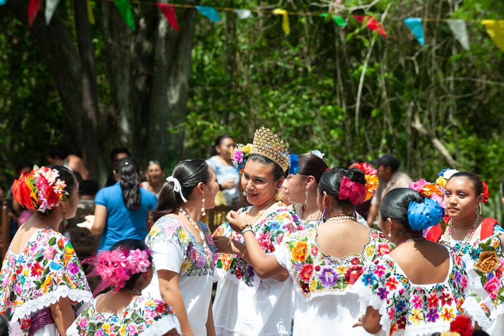 Maya women in colorful embroidered dresses gather during a community celebration near Puerto Morelos.