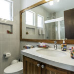 Bathroom in Apartment A#10 with vanity, large mirror, and glass shower.