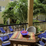 Private balcony at Apartment A#10 with table, lounge chairs, and pool garden views.