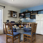 Dining area and kitchen in Apartment A#10 with balcony doors and turquoise accents.