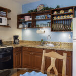 Dining area and kitchen in Apartment A#10 with balcony doors and turquoise accents.