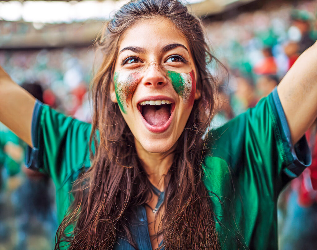 Excited soccer fan in a green jersey cheering during the World Cup.