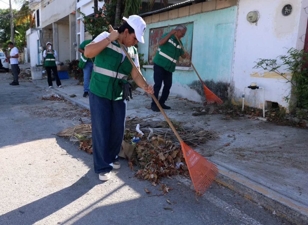 Puerto Morelos cleanup workers sweeping leaves and debris from a neighborhood street.