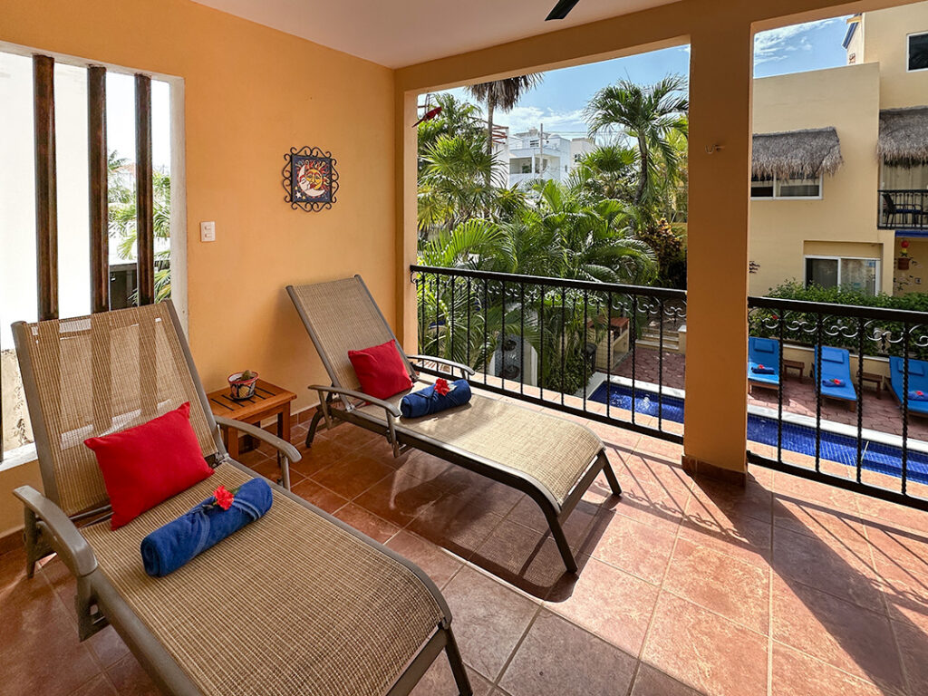 Private balcony with lounge chairs overlooking the pool and tropical garden at Apartment #10.