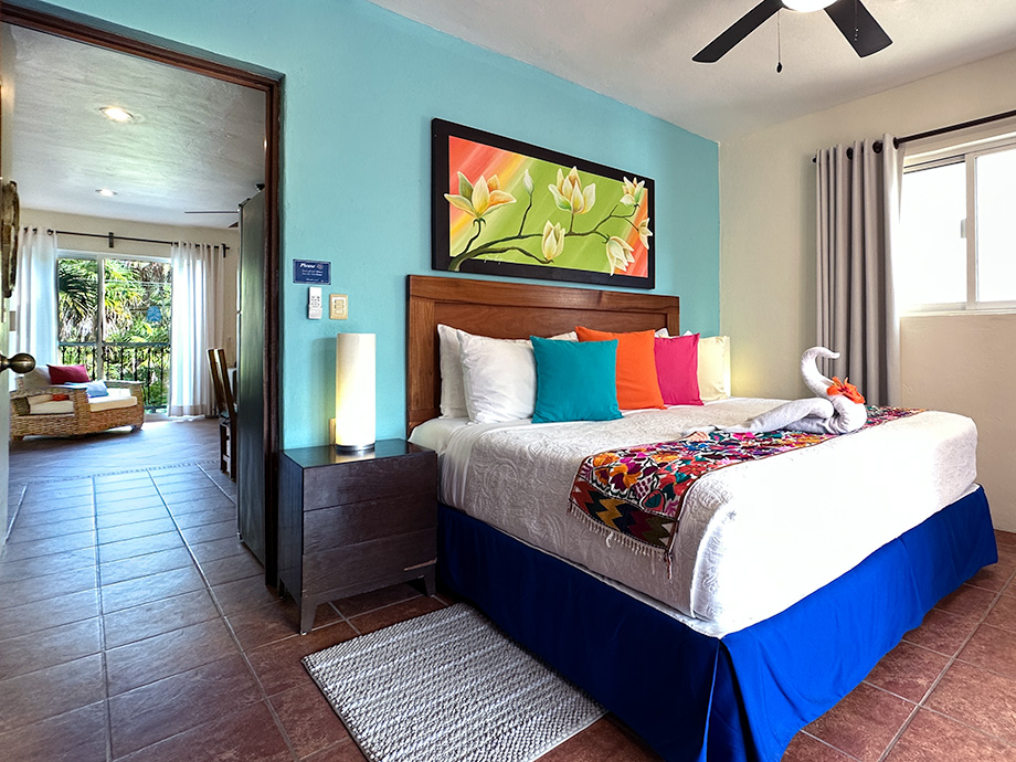 Bright king bedroom with tropical artwork and colorful accents in Apartment #10 at Abbey del Sol 2.