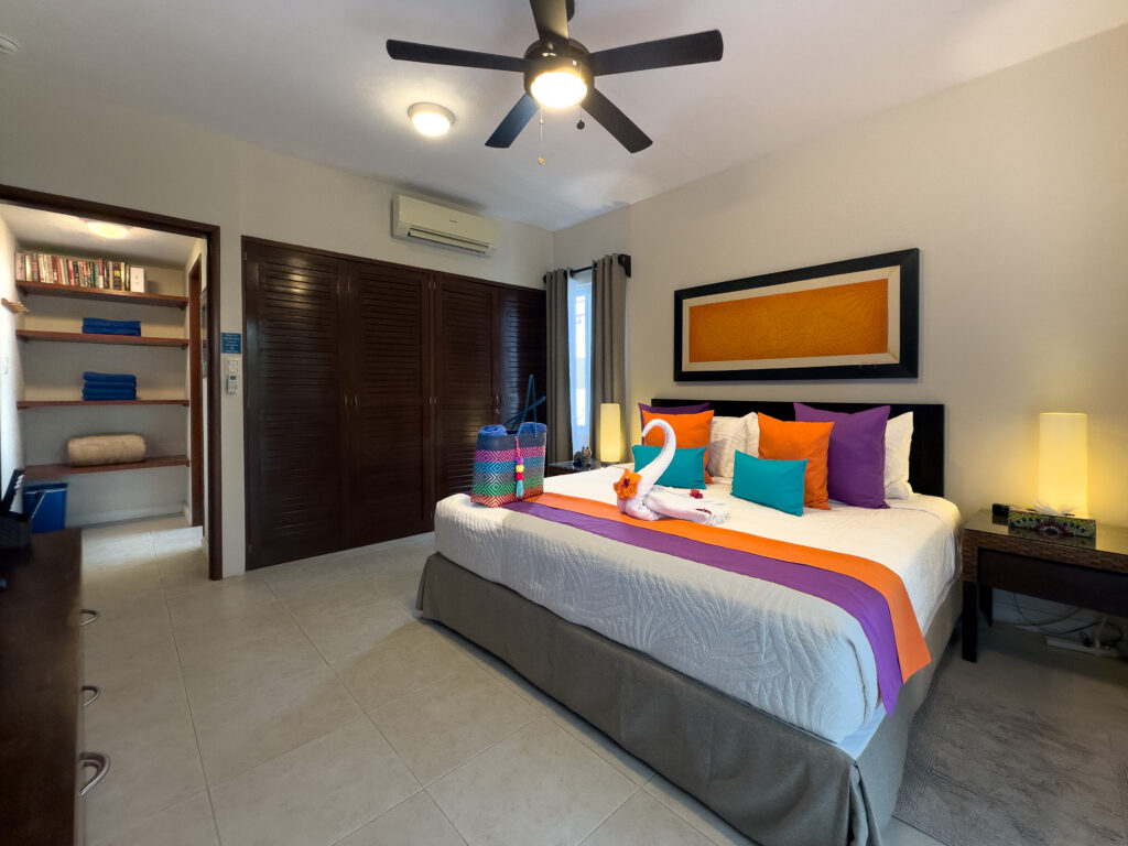 Bedroom with a ceiling fan, open shelving, wooden closets, and matching bedside lamps.
