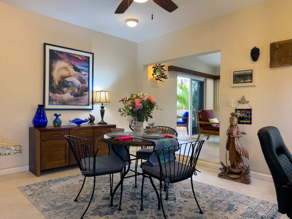 Round dining table with black chairs in front of a wooden sideboard with blue ceramics and a lamp.