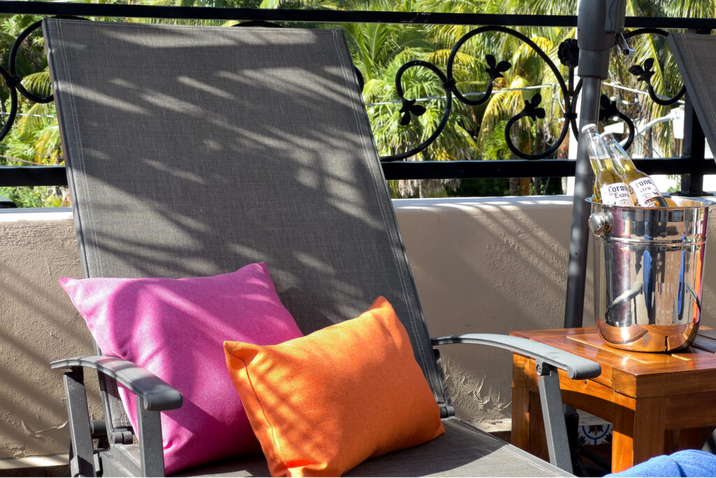Close view of a terrace lounge chair with pink and orange cushions beside an ice bucket.