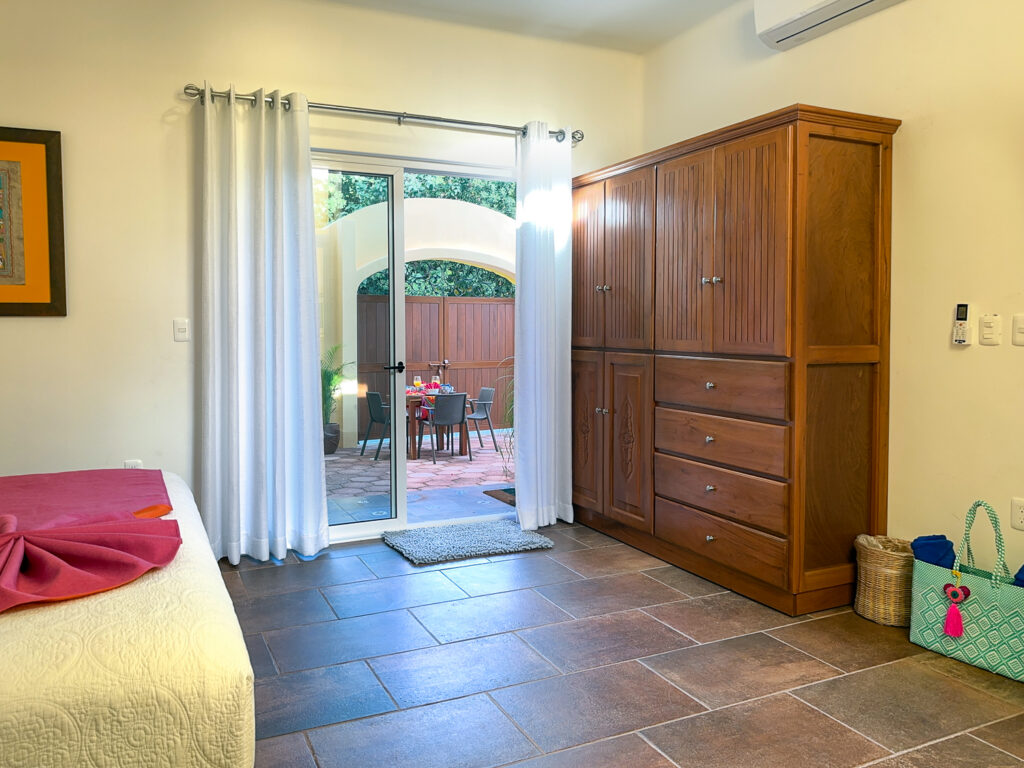 Large wooden wardrobe beside glass doors leading from the bedroom to the patio.