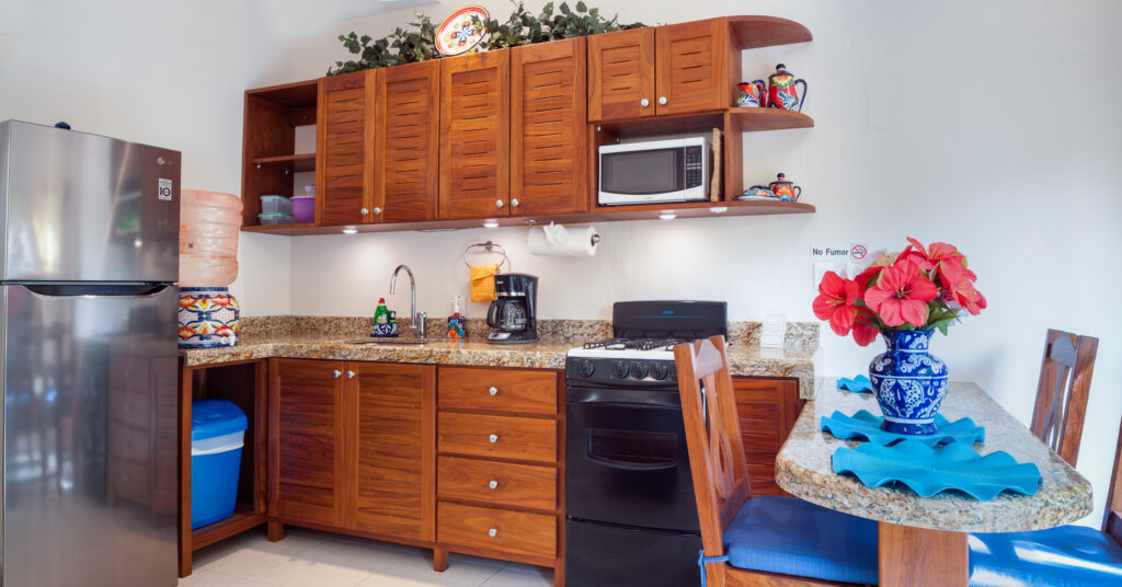 Kitchen with wooden cabinets, refrigerator, stove, microwave, and a curved counter with blue chairs.