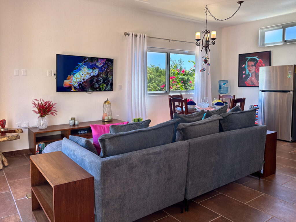 Sectional sofa facing a wall-mounted television and console beside a dining table and window.