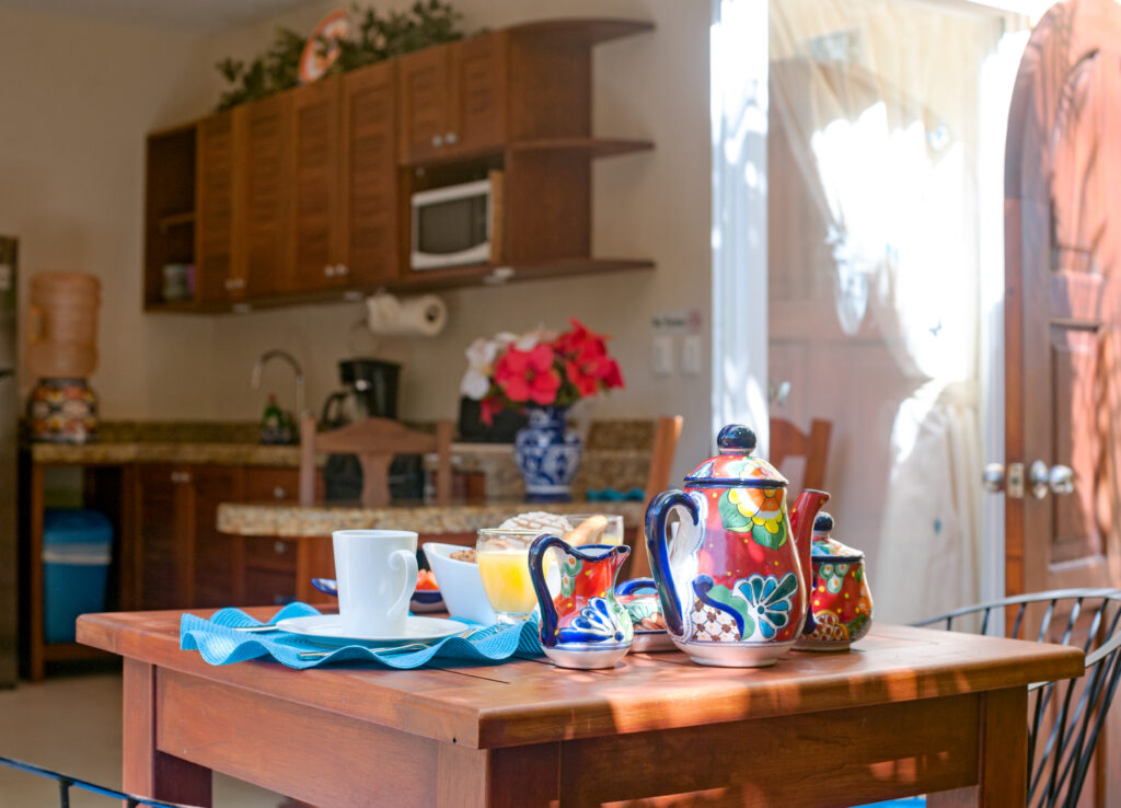 Wooden table set with colorful ceramic dishes beside the kitchen and patio door.