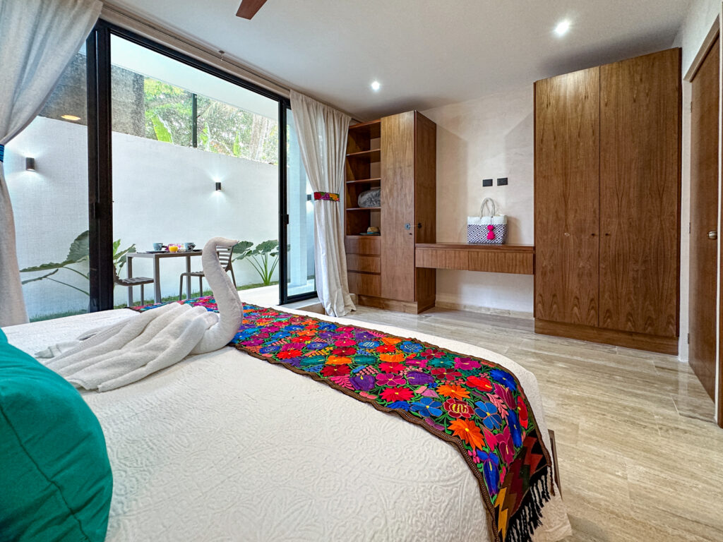 Bed facing tall wooden cabinets beside sliding glass doors to a small patio.