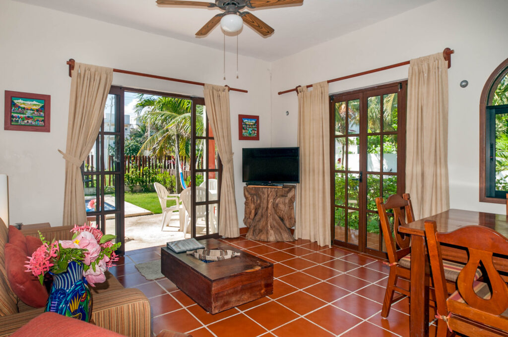Living room with wooden coffee table and television beside glass doors opening toward the garden.