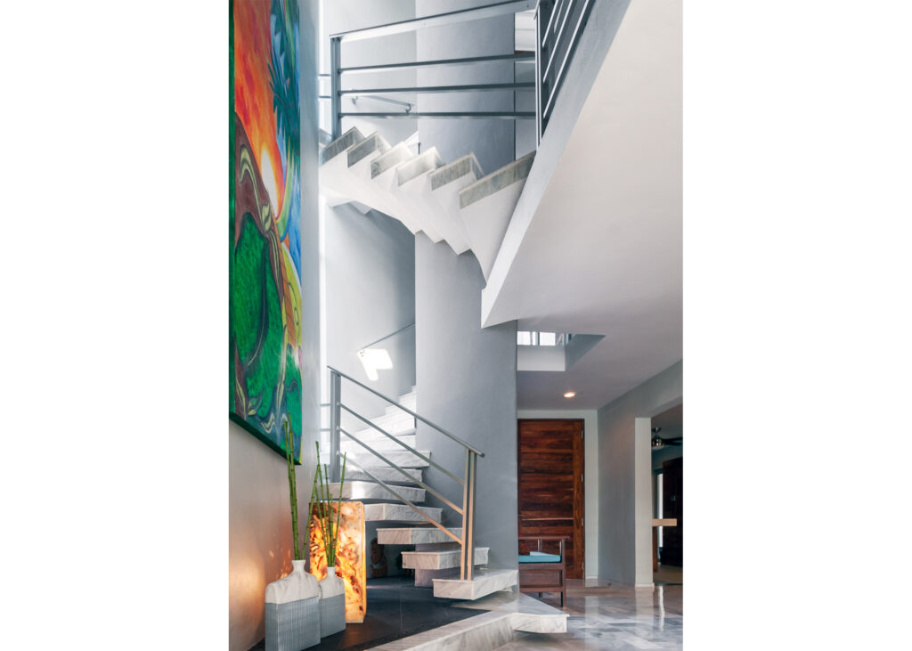 Multiple flights of open stairs and metal railings beside a tall colorful wall painting.