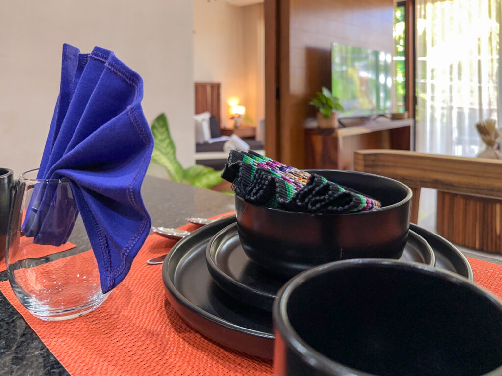 Black dishes and a blue folded napkin on an orange placemat at the kitchen counter.