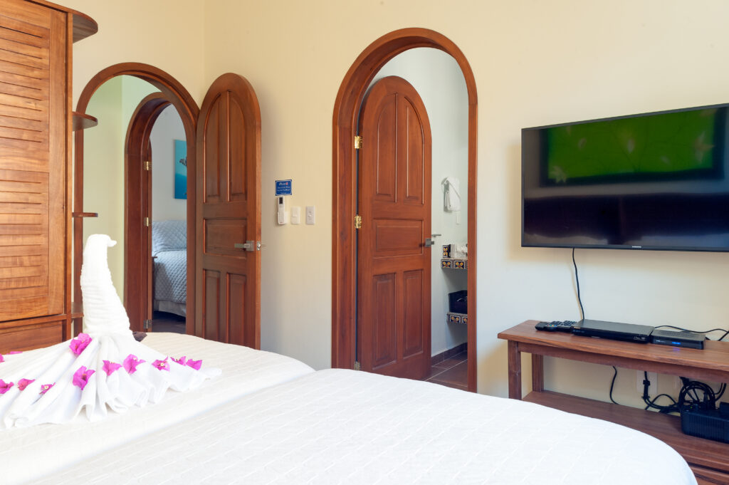 Beds with folded towel decorations facing two arched doorways and a wall-mounted television.