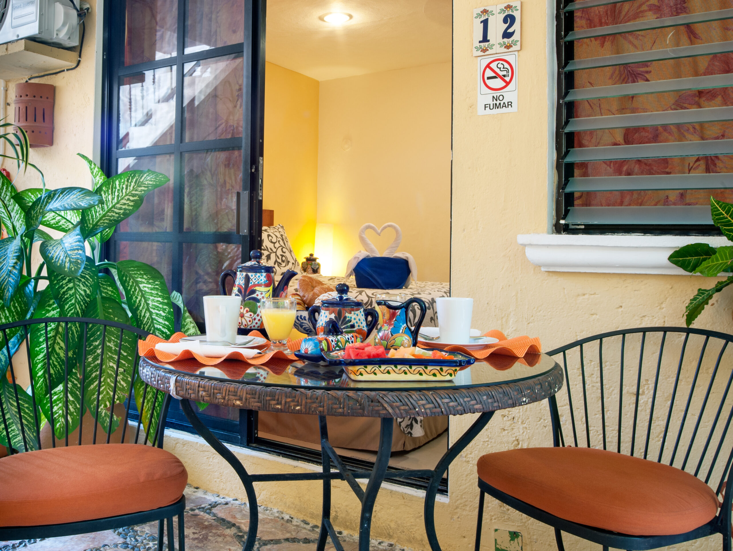 Round patio table set with colorful dishes outside the doorway marked 12.