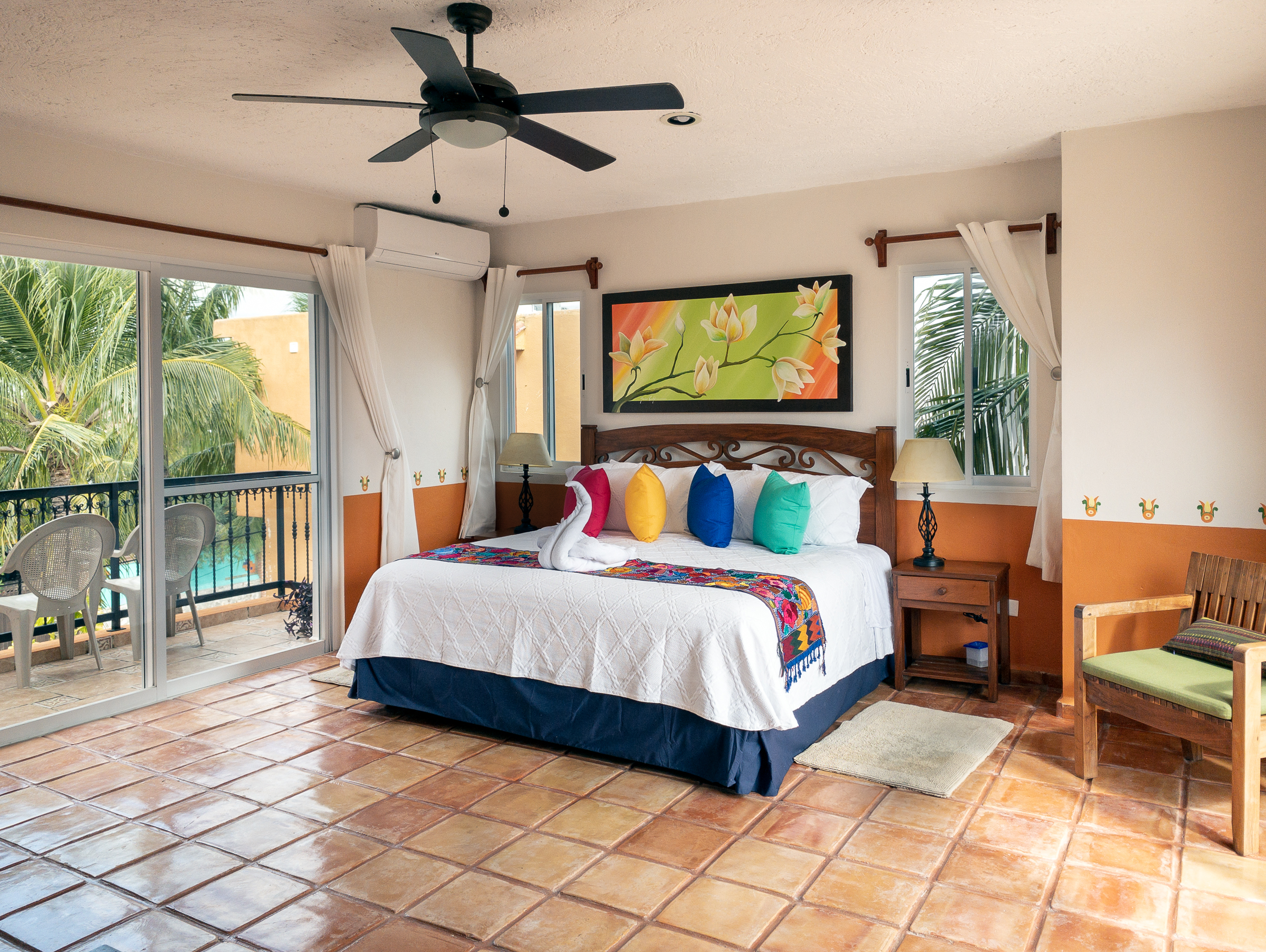 Spacious bedroom with a wooden bed, matching nightstands, ceiling fan, and terrace doors.