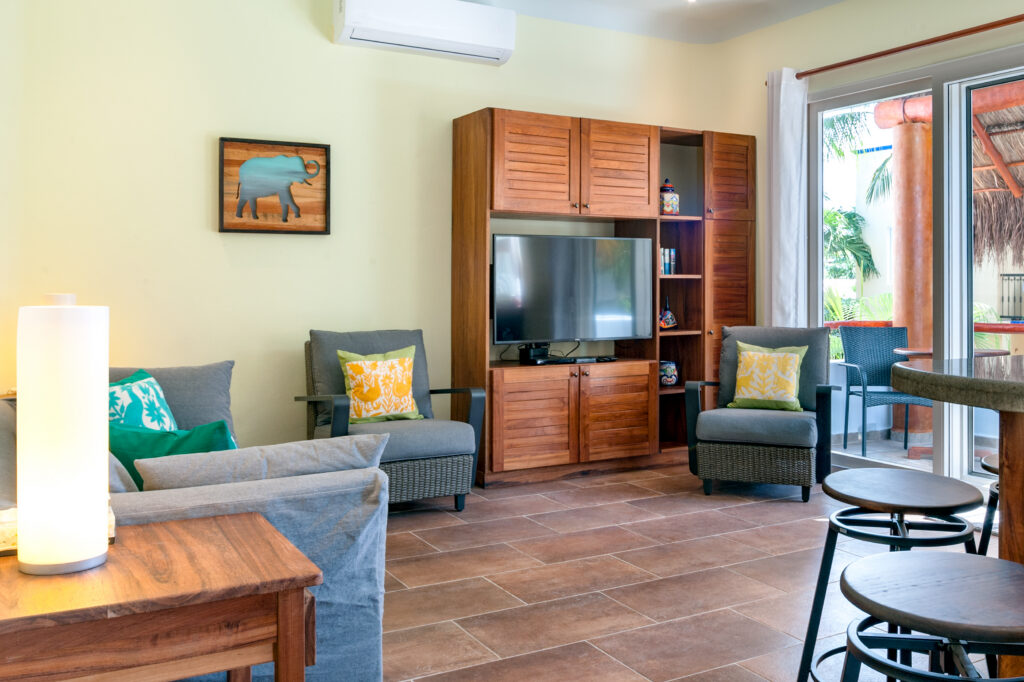 Gray sofa and two armchairs around a television cabinet near glass balcony doors.