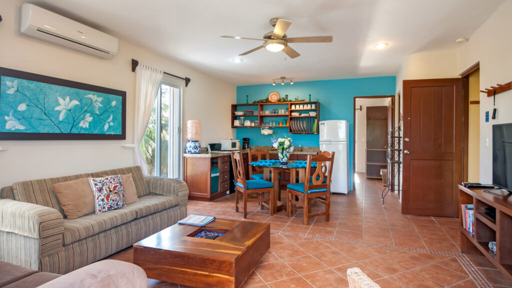 Sofa, coffee table, dining set, and kitchen arranged in an open room with a ceiling fan.