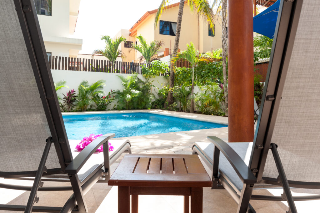 Two reclining chairs and a small wooden table facing the courtyard pool.