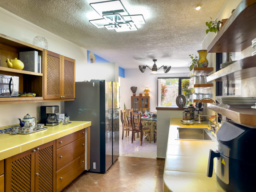 Kitchen with yellow countertops, refrigerator, and small appliances looking toward the dining area.