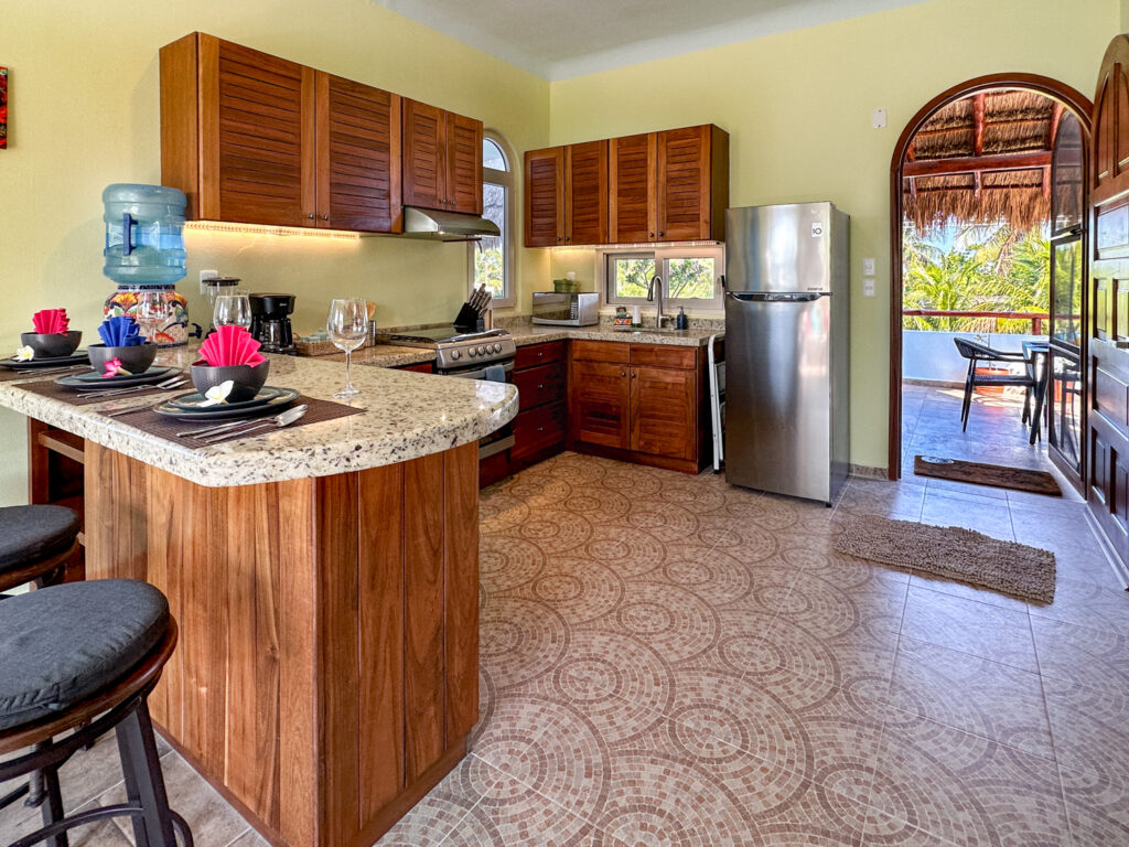 Curved kitchen counter set with dishes beside an arched doorway to the covered terrace.