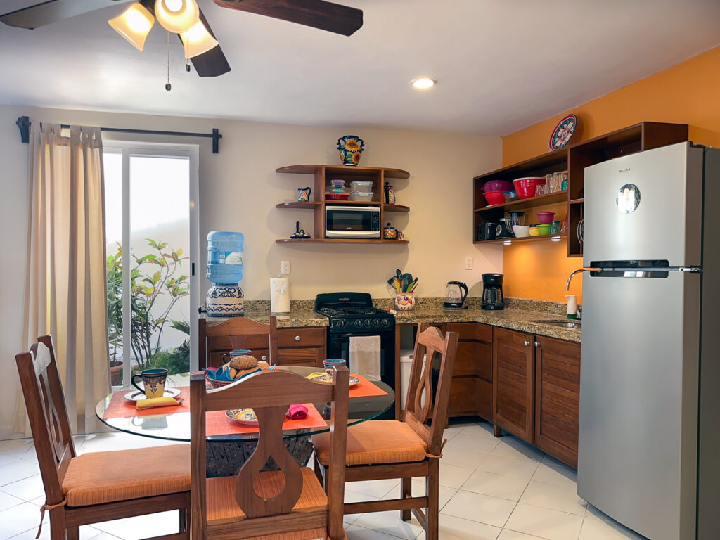 Kitchen with orange accent wall, wooden cabinets, stove, and refrigerator beside a dining table.