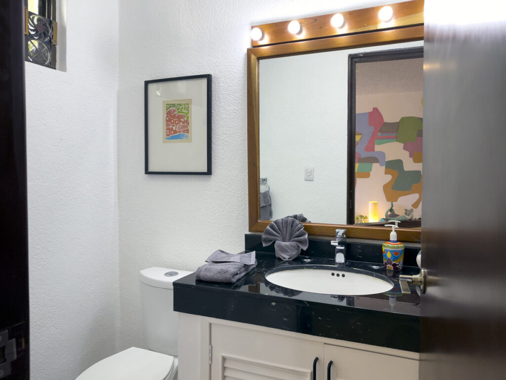 Bathroom with a dark countertop, white sink cabinet, mirror, and toilet.