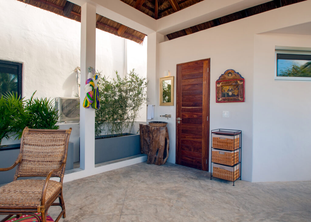 Chair and decorative wood furnishings beneath a thatched roof beside a wooden door.