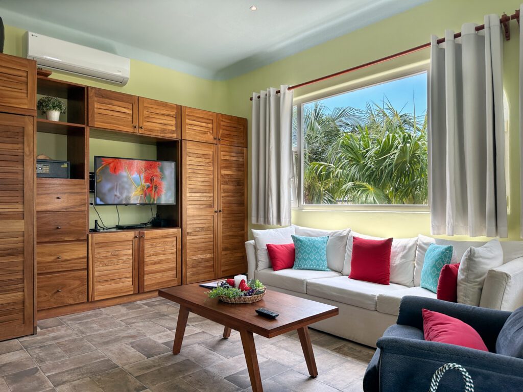 White sofa and wooden coffee table facing a television built into wooden storage cabinets.