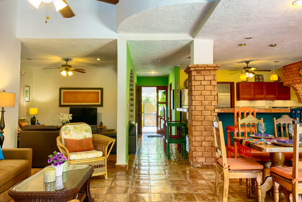 Living and dining areas beside brick columns and the colorful open kitchen.