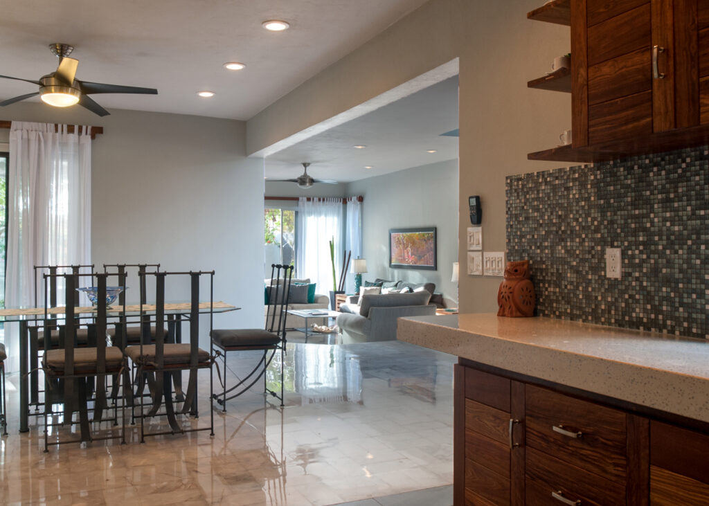 Kitchen counter with mosaic backsplash overlooks the dining area and living room beyond.