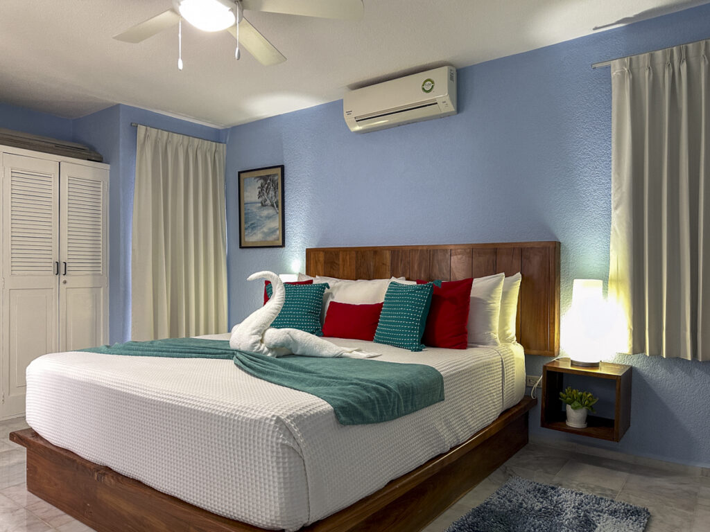 Bed with white bedding and green accents between illuminated bedside lamps in a blue-walled room.