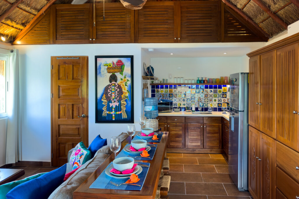 Breakfast bar, kitchen, and tall wooden storage cabinets beneath the sloping palapa roof.