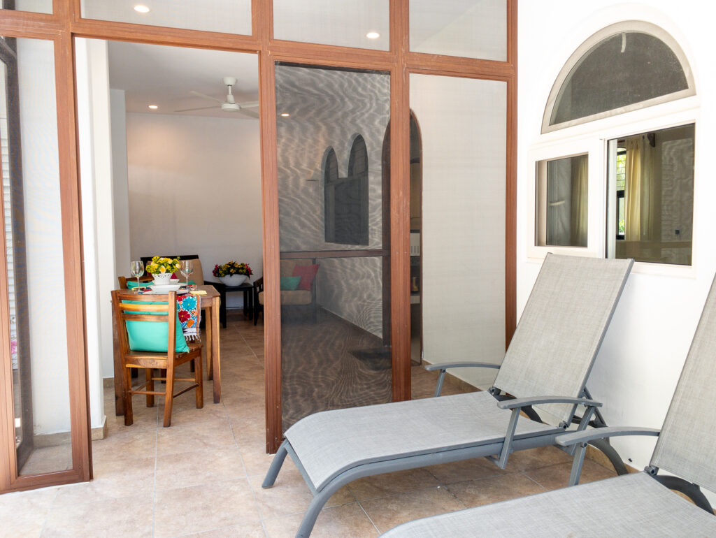 Two reclining chairs outside a screened patio, with a dining table visible inside.