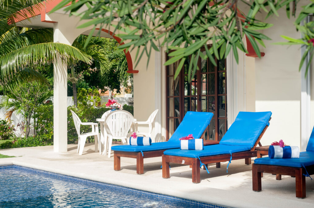 Blue lounge chairs with rolled towels beside the pool and an outdoor dining table.